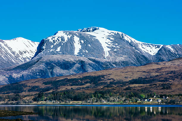 Ben Nevis, Scotland's highest mountain. Some of the most world famous and iconic ice climbs are contained on its north face. The snow corniced summit with its crags beneath, rise above the darker bulk of Carn Dearg. The easiest ascent, known as the tourist path, can be seen zigzaging up the grey scree slopes to the right of centre. Many walkers are caught unawares on this apparently easy route to a relatively low altitude peak, starting off in trainers and teeshirt, only to return by stretcher. AdobeRGB colorspace.