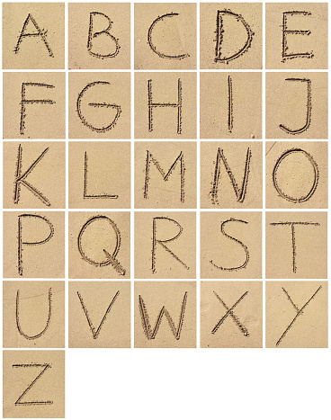 Alphabet drawing or writing in the sand. Arrangement of letters in the sand.