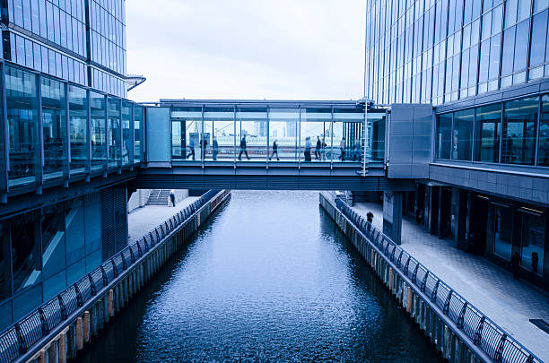 moderne wolkenkratzer mit brücke zwischen zwei fluss - büropark stock-fotos und bilder