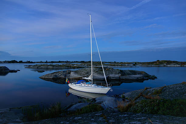 Blue midnight light over a mored sailingboat in the outer archipelago of Stockholm, Sweden