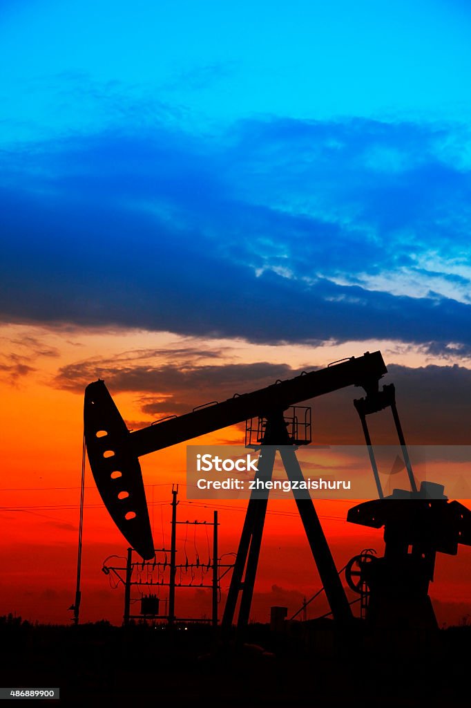 The oil pump Oil field scene, the evening of beam pumping unit in silhouette 2015 Stock Photo