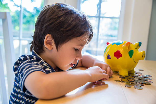 Counting Money Little boy counts money on a table with his piggy ban beside him counting coins stock pictures, royalty-free photos & images