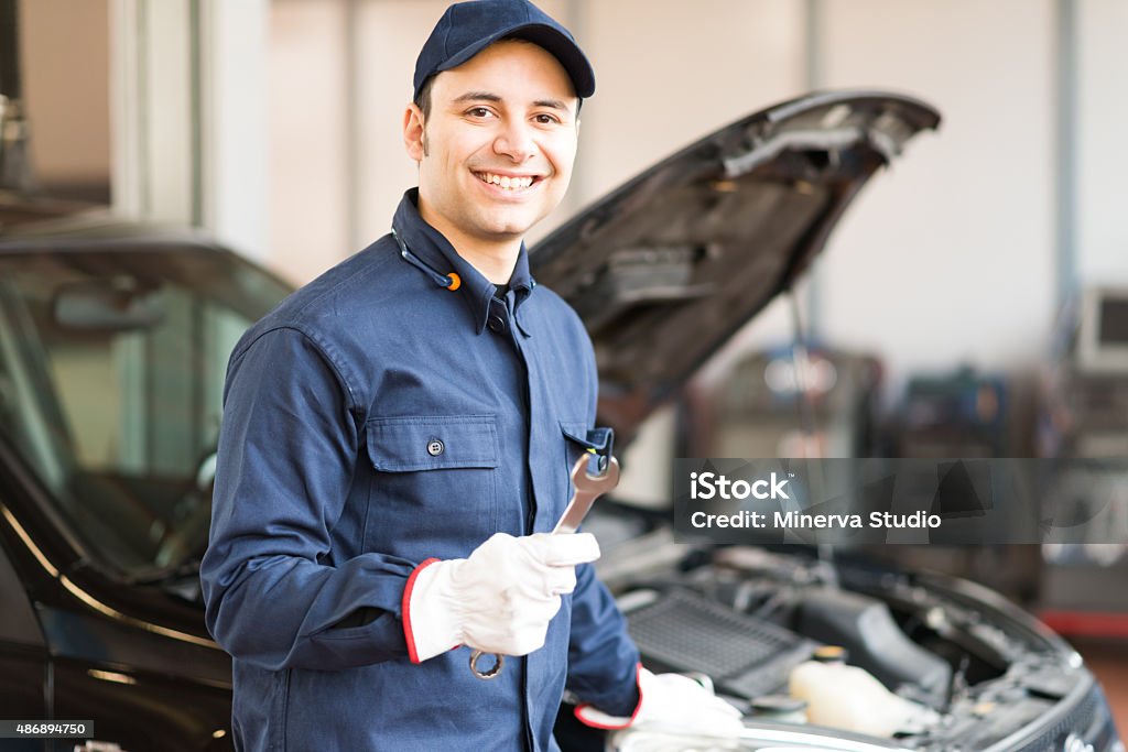 Portrait of a mechanic holding one wrench Portrait of a smiling mechanic holding a wrench in his garage 2015 Stock Photo