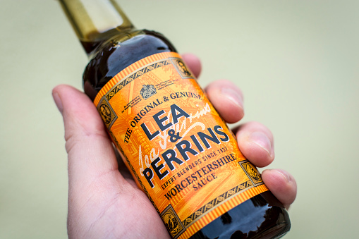 Poole, UK - September 11, 2015: Close up of a male hand holding a bottle of Lea & Perrins Worcestershire Sauce - a popular condiment / cooking ingredient.
