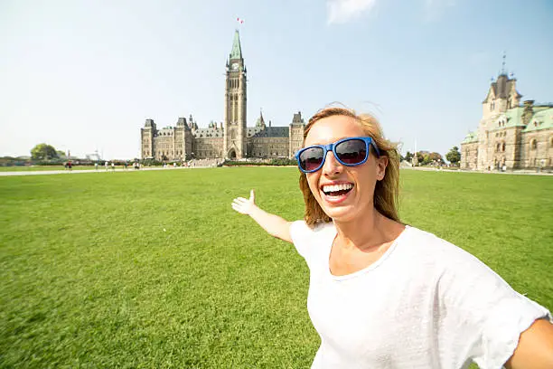 Photo of Cheerful woman in Ottawa taking selfie portrait with parliament house