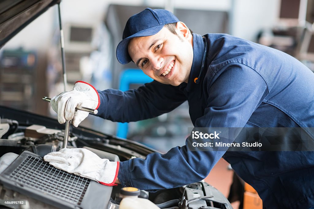 Smiling mechanic fixing a car engine Portrait of a smiling fixing a car engine in his garage Auto Mechanic Stock Photo