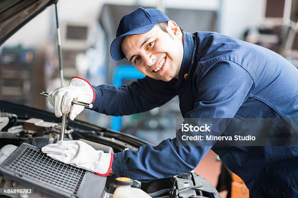 Smiling Mechanic Fixing A Car Engine Stock Photo - Download Image Now - Auto Mechanic, 2015, Auto Repair Shop