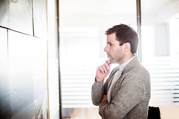 istock Businessman examining plan on wall in brightly lit office 486896046