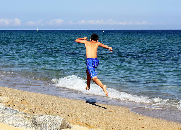 istock Boy running on the sea beach 486896307
