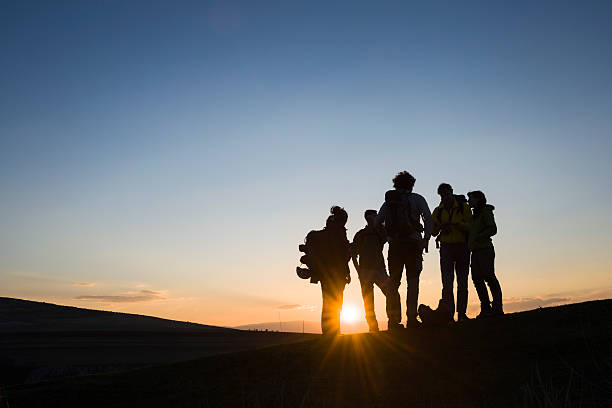 Bunch of friends with backpacks at sunrise stock photo