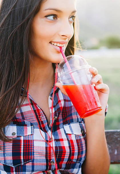 istock Girl drinking red smoothie in park 486896840