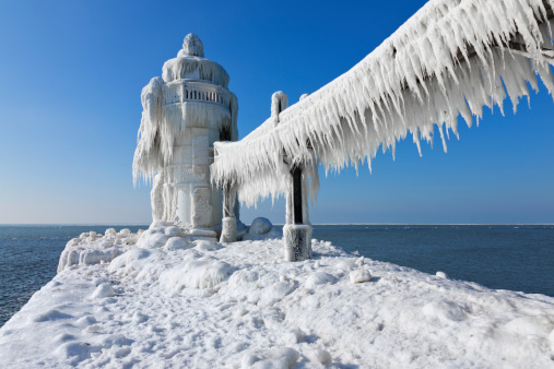 St. Joesph Lighthouse is encased in ice on this frigid winter day on Lake Michigan. Curtains of ice hang like curtains from the catwalk as a result of the dramatic storms the Great Lakes provide.