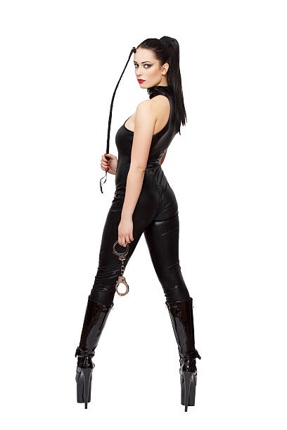 Sexy woman in latex catsuit and boots holding whip Sexy woman in latex catsuit, boots and whip, isolated on white background dominatrix stock pictures, royalty-free photos & images