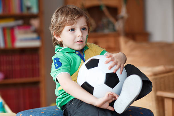 istock Little boy with football watching soccer 486899707