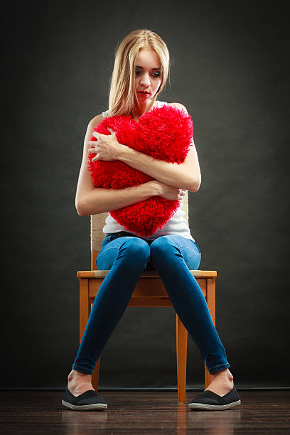 istock Sad unhappy woman holding red heart pillow 486911348