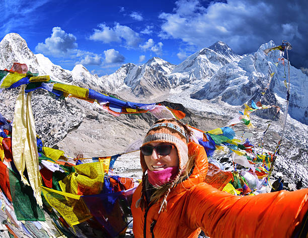 Smiling young woman takes  selfie  on mountain peak  Kala Patthar stock photo