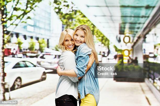 Smiling Women Hugging At Street In The City Stock Photo - Download Image Now - Cityscape, Embracing, Vanishing Point