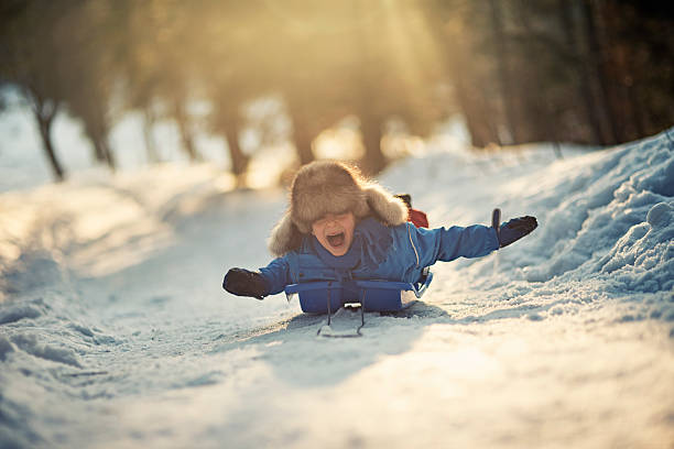 niño divirtiéndose en su sled en invierno worest. - deslizarse en trineo fotografías e imágenes de stock