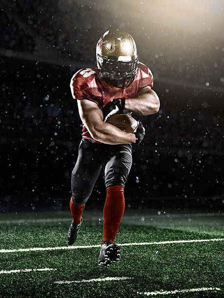American football player A male american football player makes a dramatic play. The stadium is dark behind him. american football player studio stock pictures, royalty-free photos & images