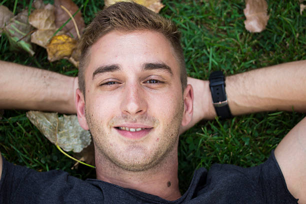 istock Close up of young man face, laying in grass. 486922116