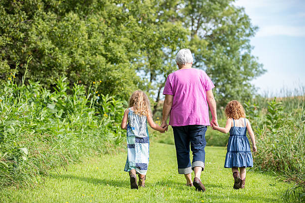 istock Two Girls & Grandma Walking on Grass Trail 486922898