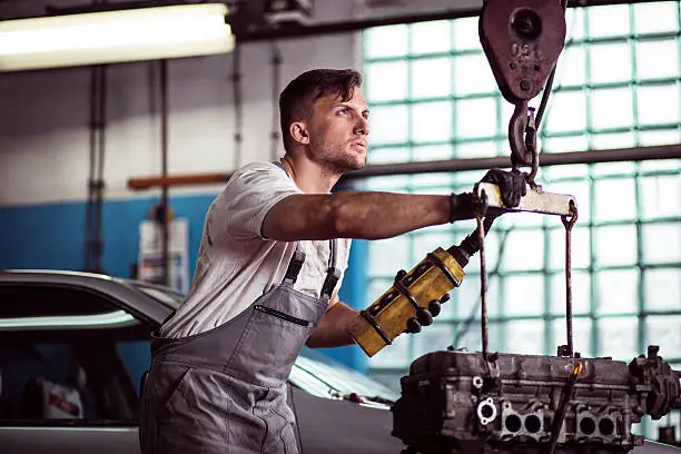 Image of auto workshop worker using engine hoist