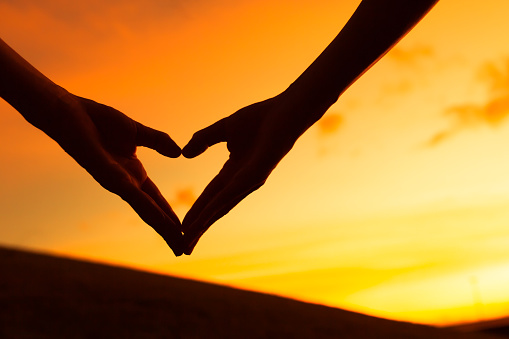 Love shape hands against natural background.