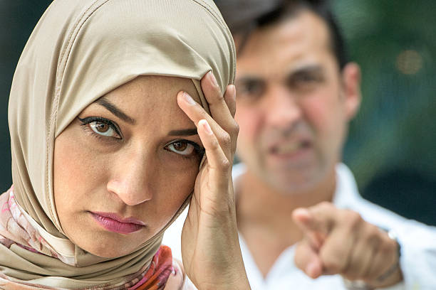 Relationship Difficulties serious muslim woman and a very upset man in the background, they're arguing muslim divorce stock pictures, royalty-free photos & images