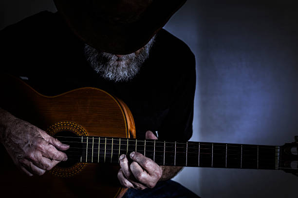 istock Senior Man Playing Acoustic Guitar in Dark Room 486929430