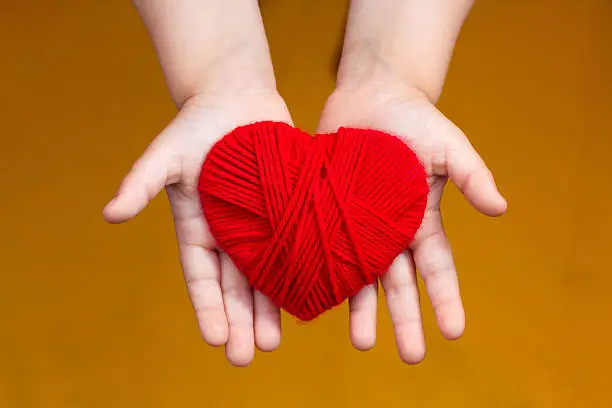 Heart of thread in the hands of a child