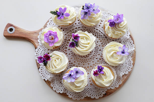 istock Homemade purple freesia flowers on vanilla cupcakes with whipped 486930708