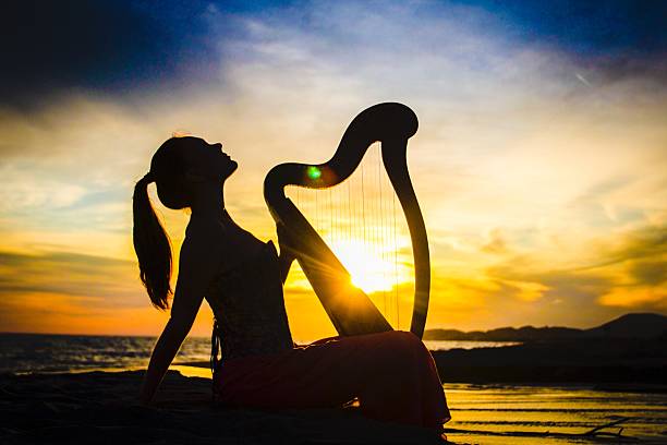 istock Fairytale harpist silhouette with celtic harp on sunset 486934354