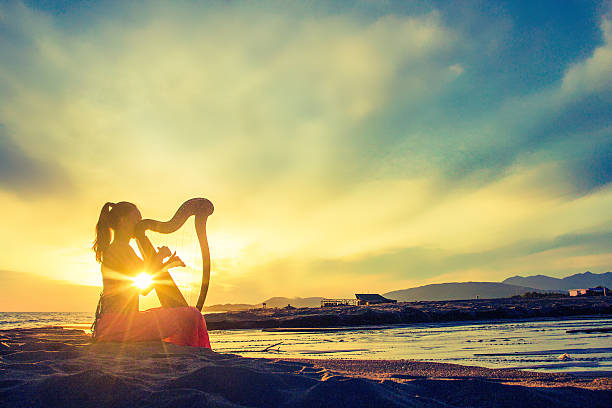 Fairytale harpist silhouette with celtic harp on sunset