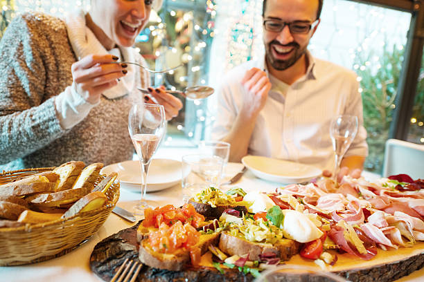 couple having рождественский ужин в ресторане - antipasto prosciutto italian culture ham стоковые фото и изображения