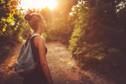 Photo of a young woman with a backpack, wandering around in nature and relaxing