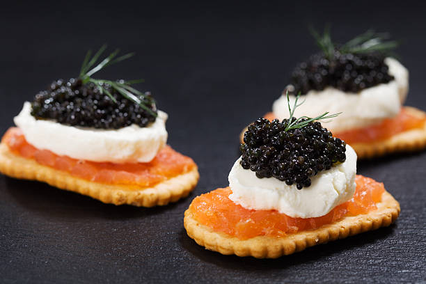 istock Black caviar served on crackers with salmon and cream cheese. 486939048