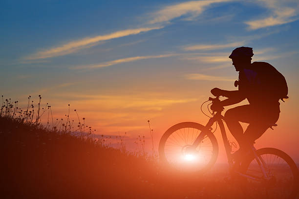 istock Silhouette of a biker and bicycle on sunset background. 486941310