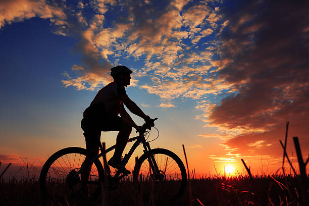 istock Silhouette of a biker and bicycle on sunset background. 486941378