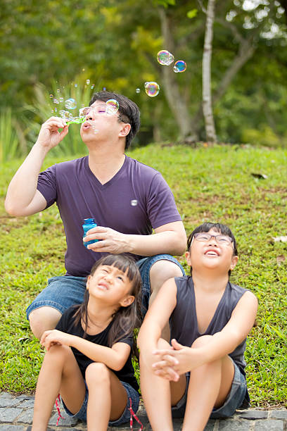 istock Young Asian girl playing blowing bubbles in park bonding 486945914