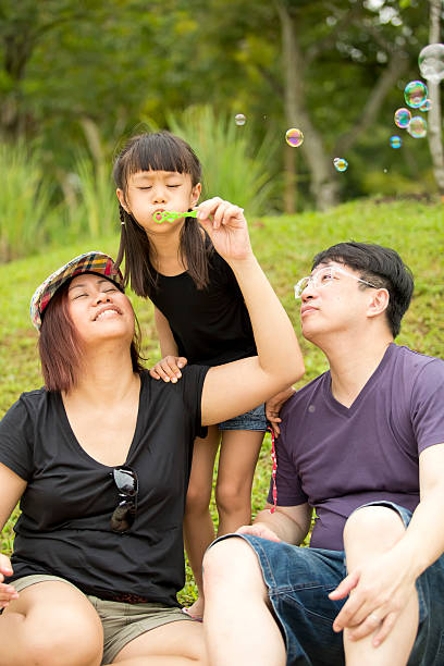 istock Young Asian girl playing blowing bubbles in park bonding 486951078