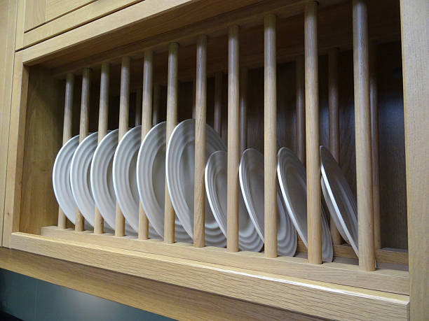 Image of wooden plate rack filled with white dinner plates Photo showing a kitchen with a wooden plate rack made from beechwood that is filled with a row of white dinner plates, which are easy to access and right at hand, hanging on the wall and ready for a family meal. plate rack stock pictures, royalty-free photos & images