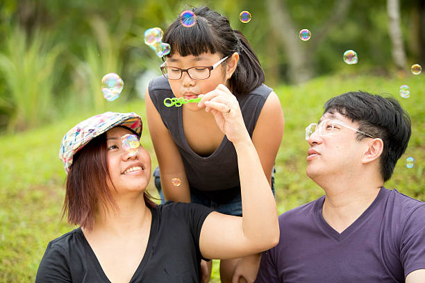 istock Young Asian girl playing blowing bubbles in park bonding 486954962