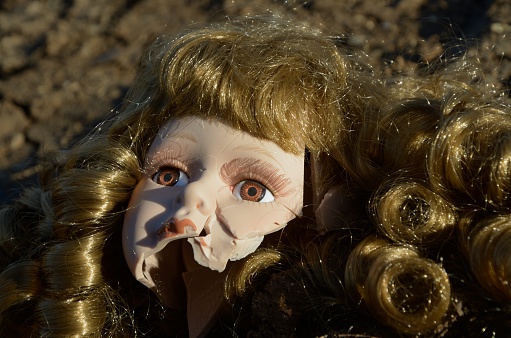 Broken doll head on the ground