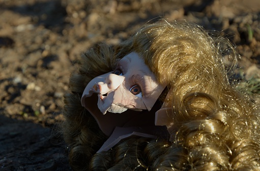 Broken doll head on the ground