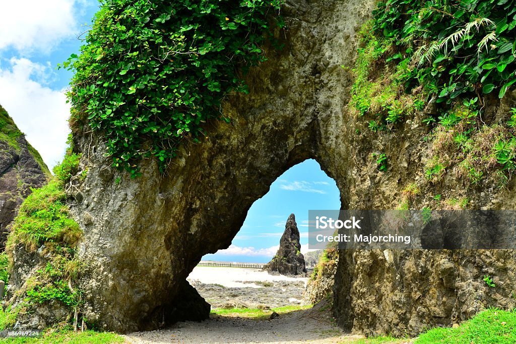 Peculiar rocks and cave beside seashore Peculiar rocks and cave beside seashore. Green plants grow on peculiar rock,the rock look alike a elephant head. White clouds floating at blue sky, sunlight and sunny weather. Travel location: Green Island,in Taiwan. Green Island - Taiwan Stock Photo