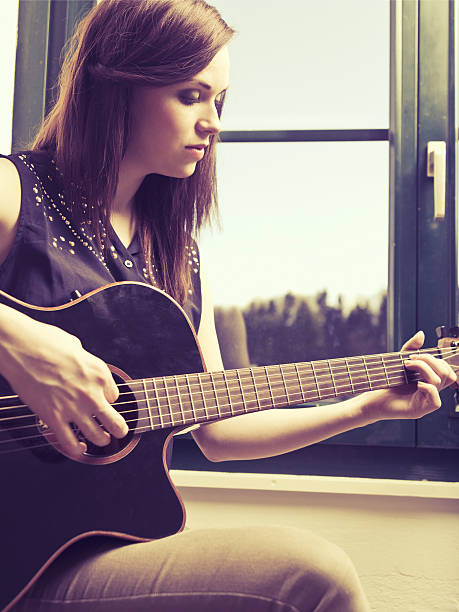istock Playing acoustic guitar by the window 486972715