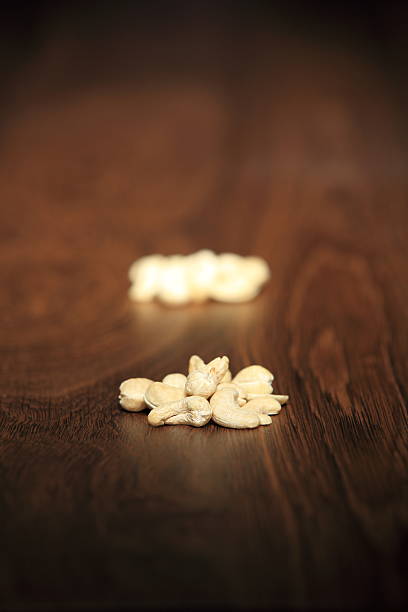 two piles of nine cashew nuts on wood two piles of nine cashew nuts on wood with shallow depth of field - series conceptional stock pictures, royalty-free photos & images