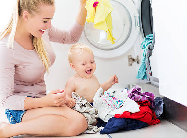 istock Mother and baby loading clothes into washing machine 486973292