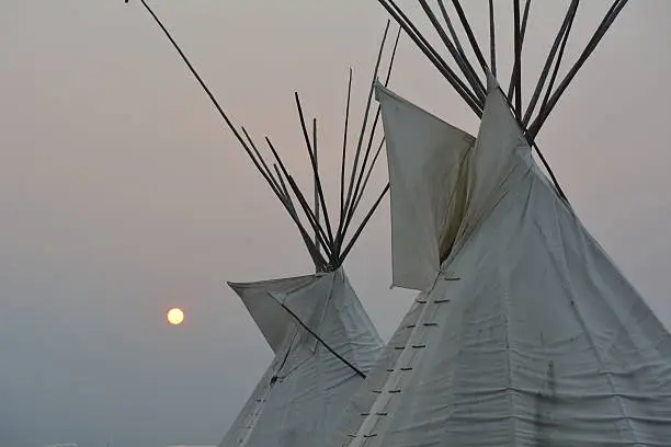 professionally set up tipi's with sun setting in background.