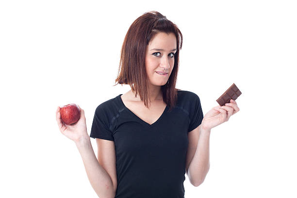 istock Young woman torn between a chocolate bar and fresh apple 486976443